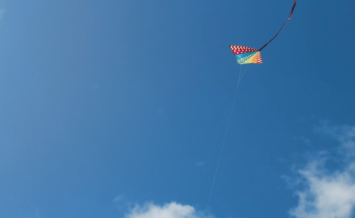 Multi-coloured kite against blue sky signifies organisations embedding transformation